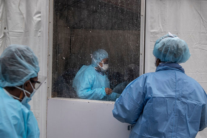 DACA heath care workers putting PPE on in a tent