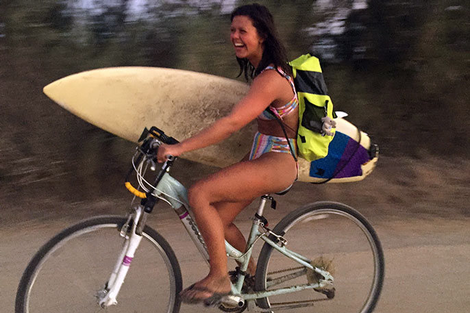 Katia Gibson bicycling with her surfboards