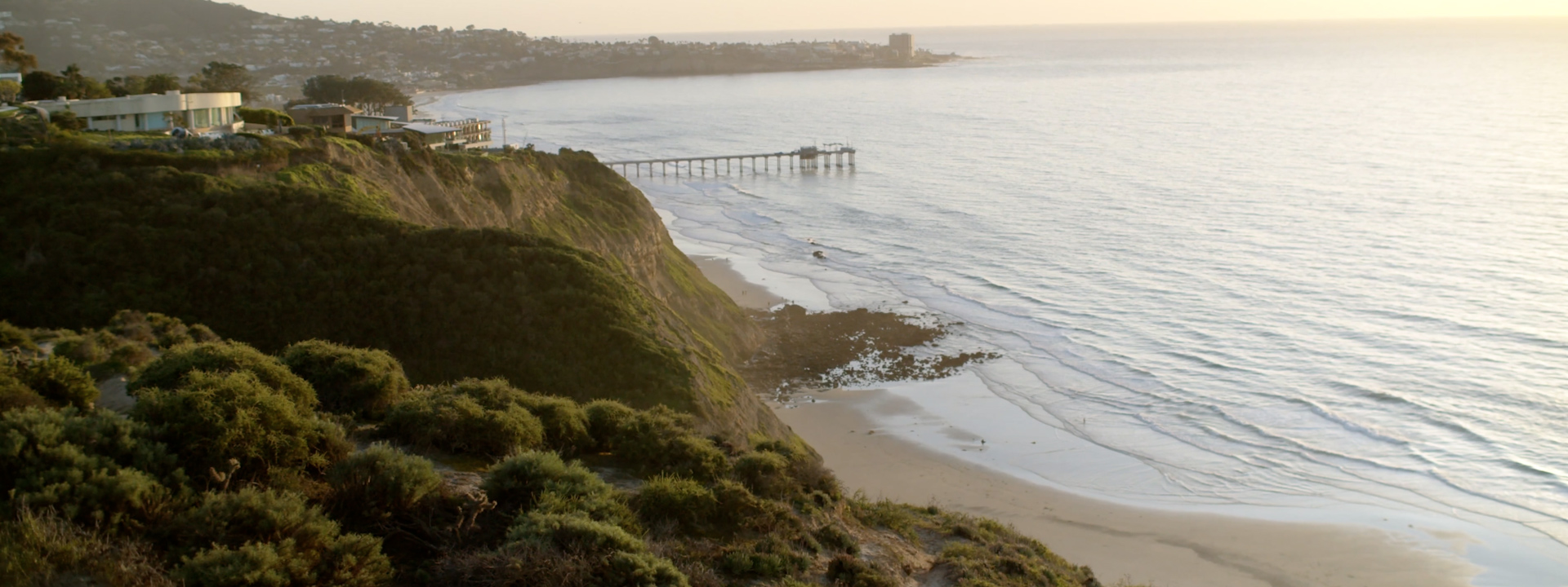 Elevated view of a beach, pier and bluffs at sunset