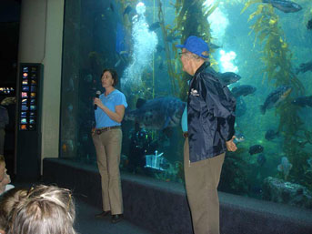 Megan speaking at Birch Aquarium in front of fish tank