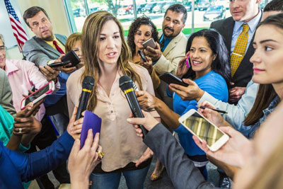 Woman stands in a crowd of microphones