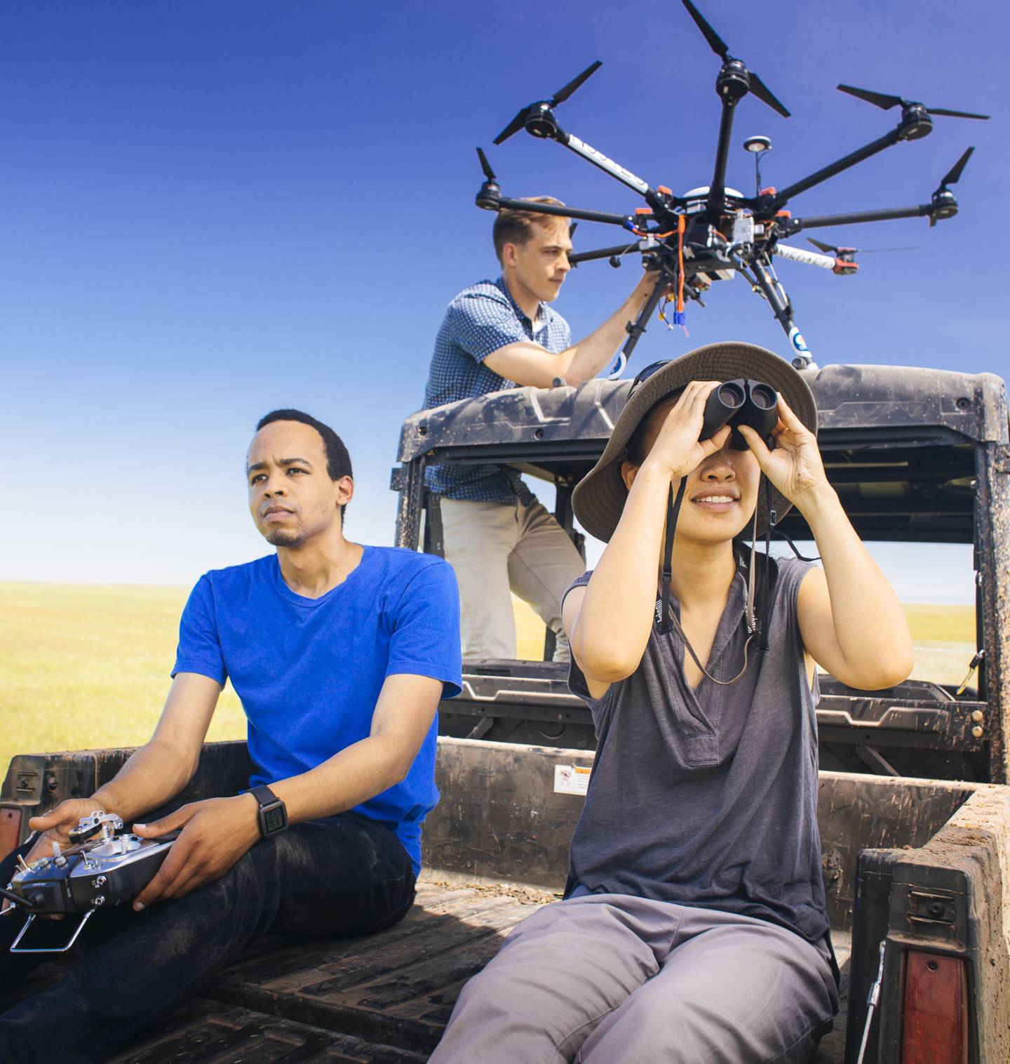 Student researchers on the back of a truck working with a drone