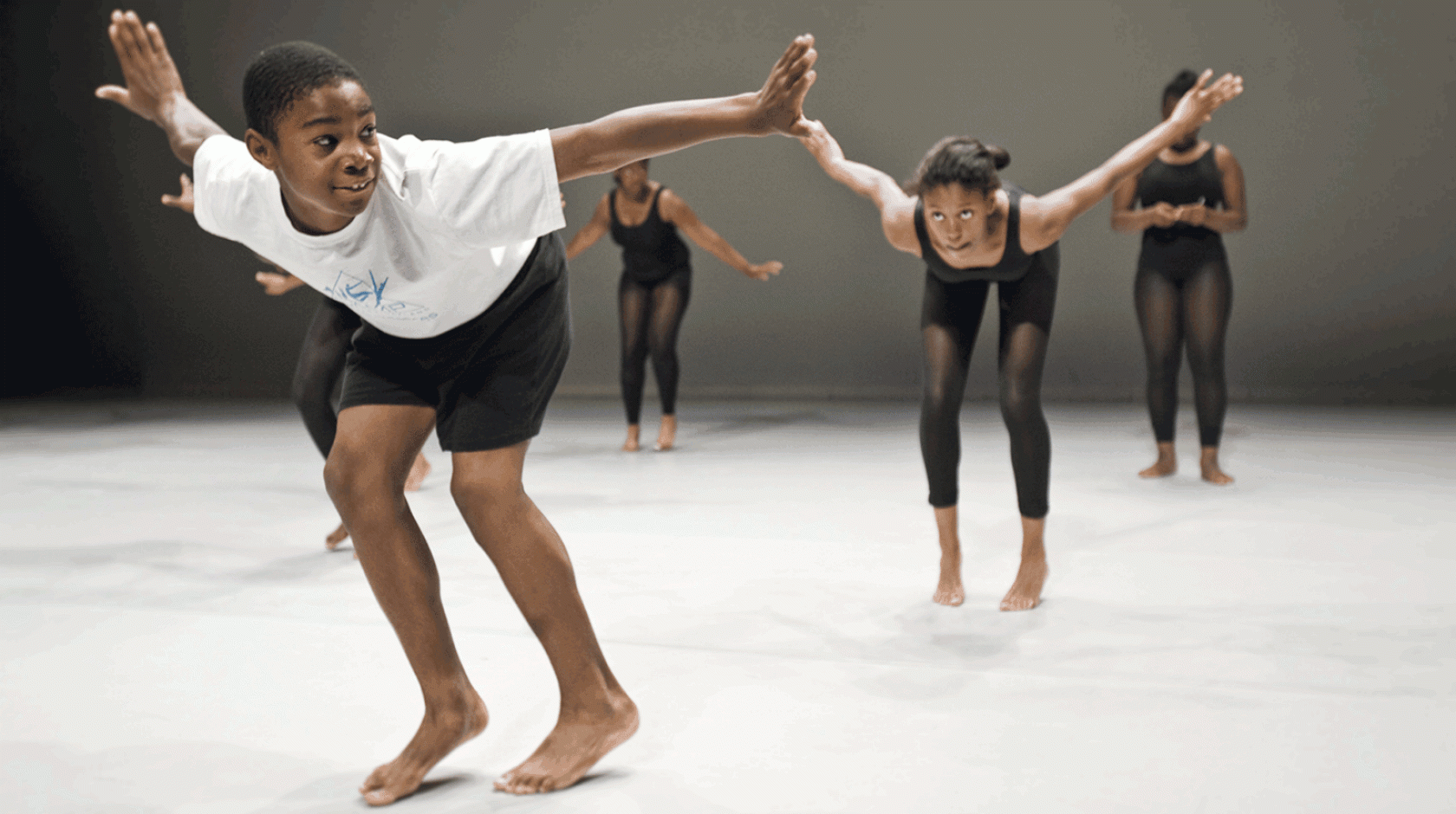 Camilo Eifler and three other dancers on stage, leaning forward dynamically with their arms outstretched