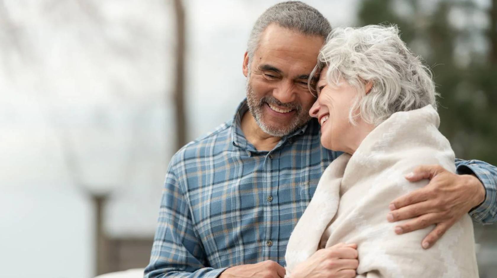 Older man and woman smile and embrace