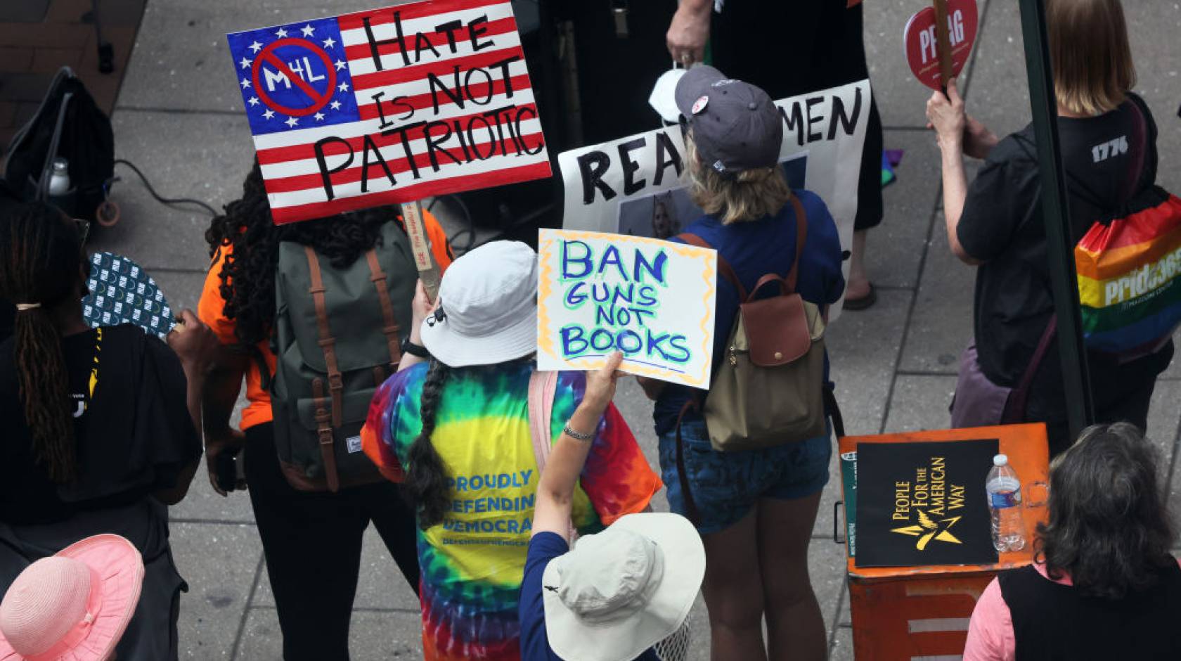 People at a protest holding signs, one reading "Ban guns not books"