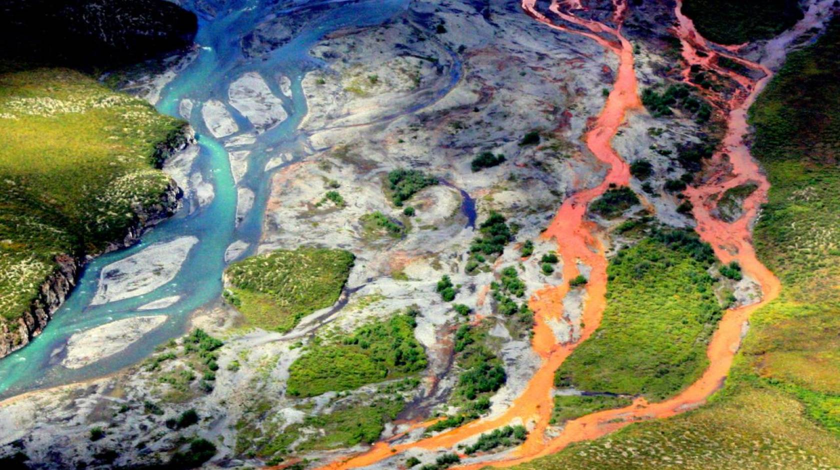 Aerial view of a braided river flowing through a tundra. The channels on the right side of the image are bright orange.