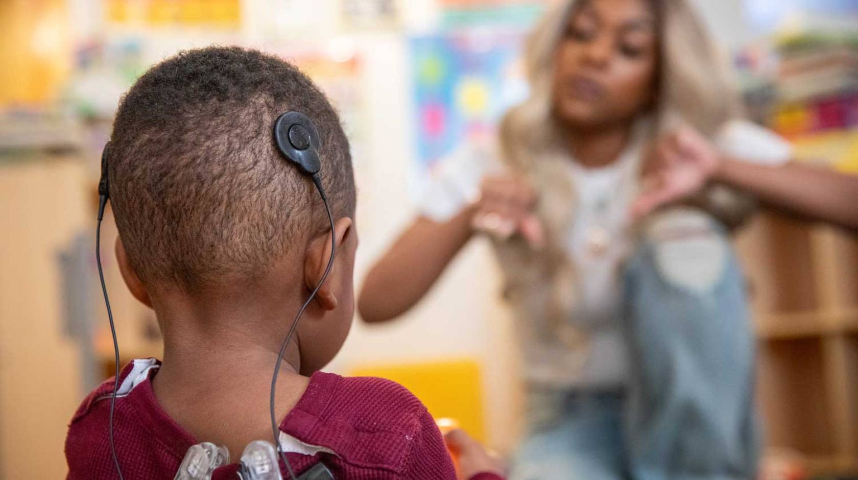 A boy wearing a black headset looks at his mom