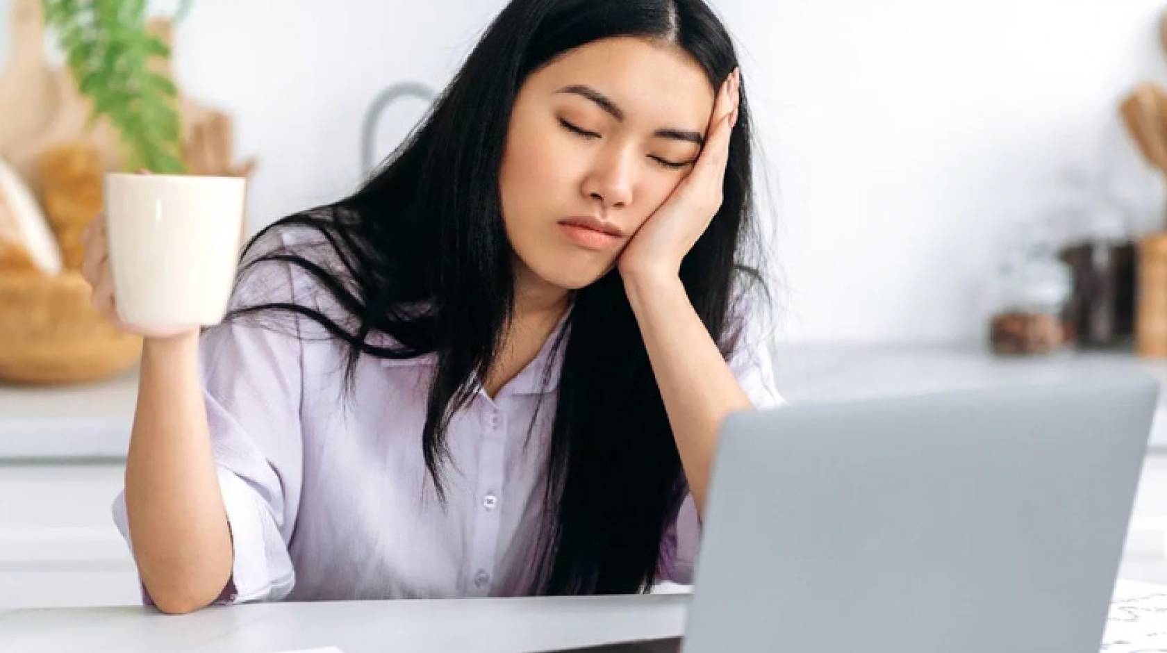 A young woman asleep in front of a laptop