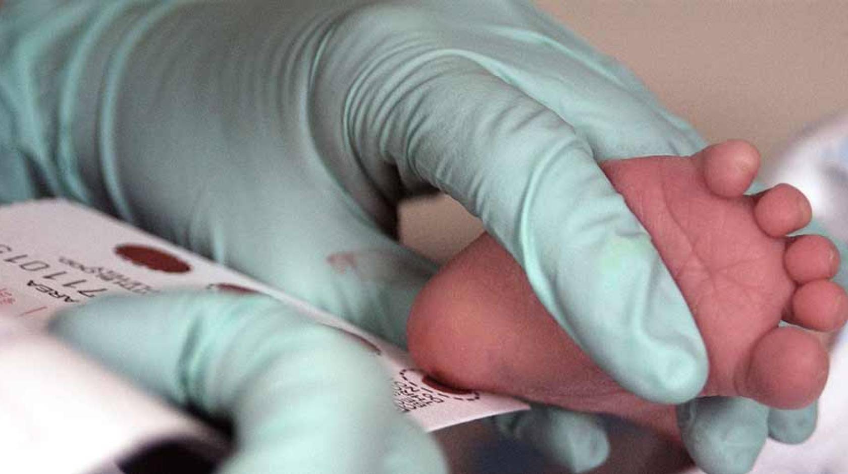 Baby's foot held by doctor for a blood test