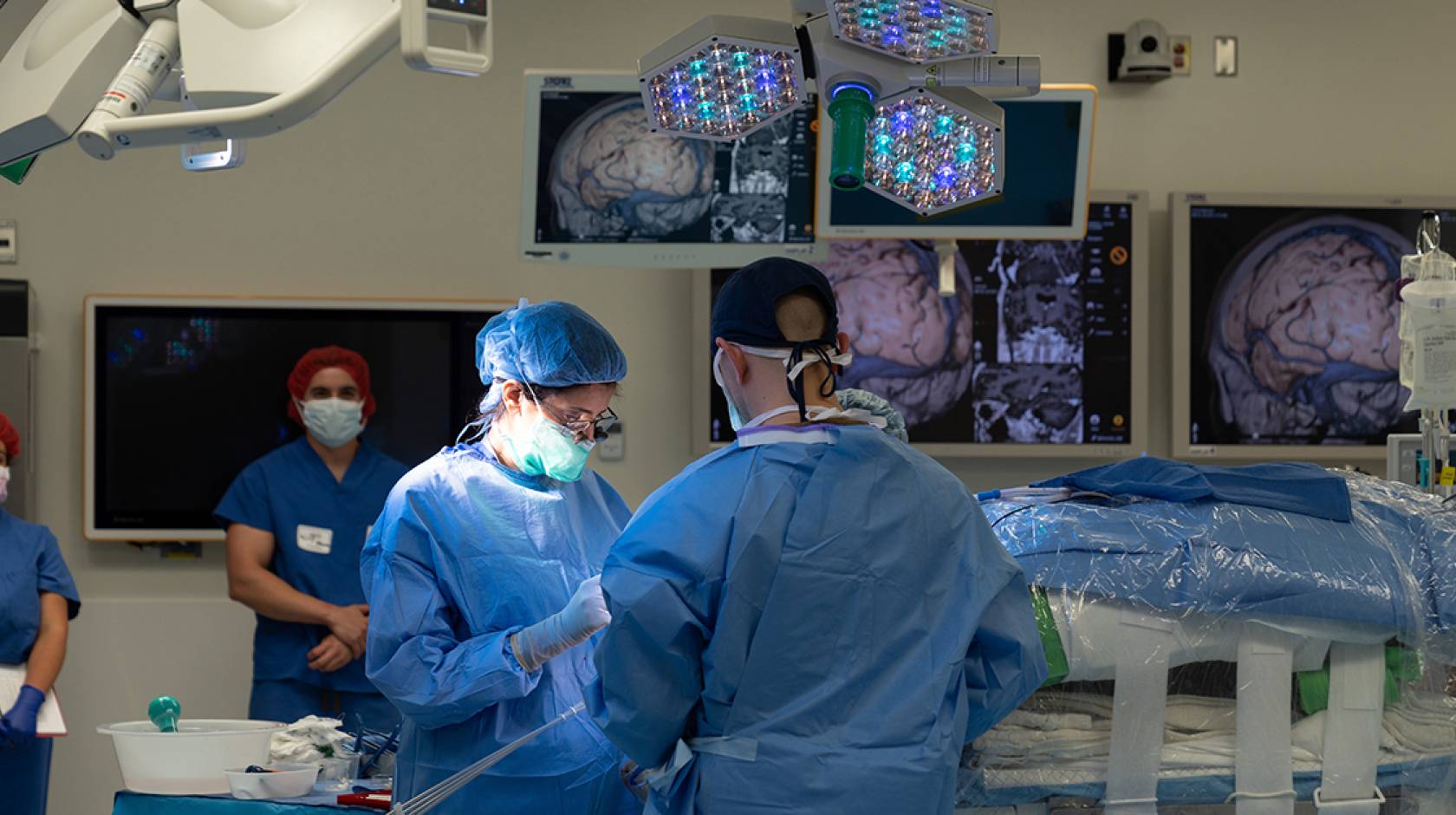 Surgeons operating in an operating room with brain scans hanging around the theater