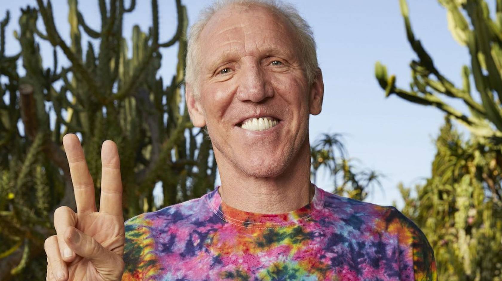 Bill Walton flashes a peace sign while wearing a tie-dyed shirt