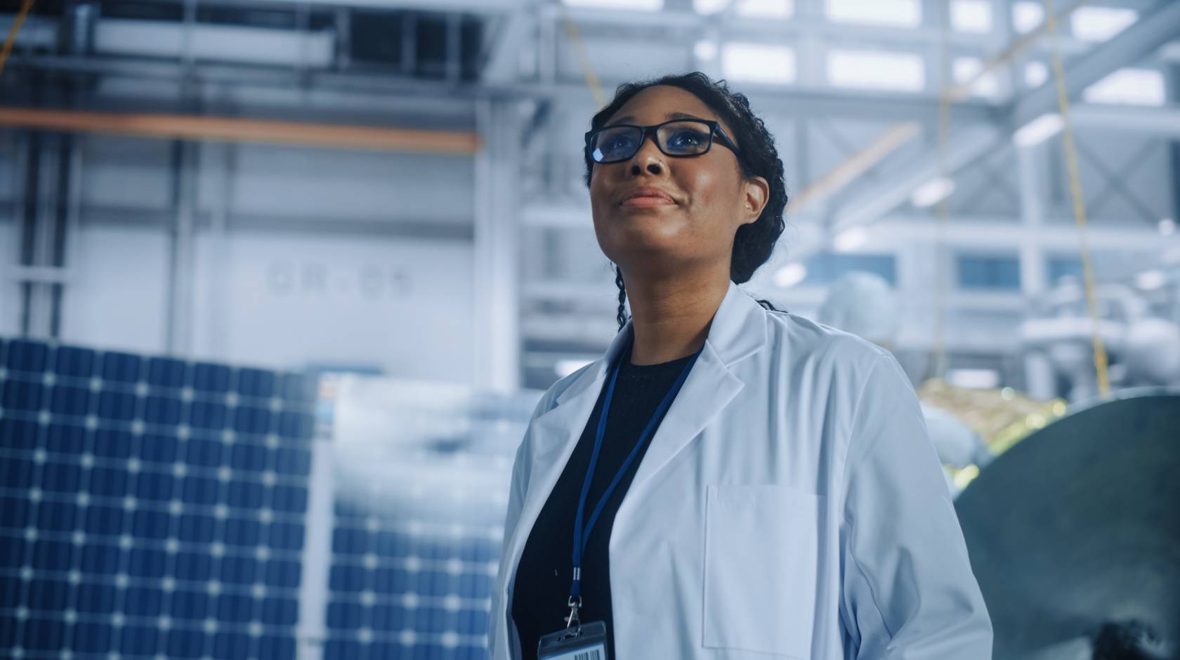 Black woman scientist looking up in a warehouse