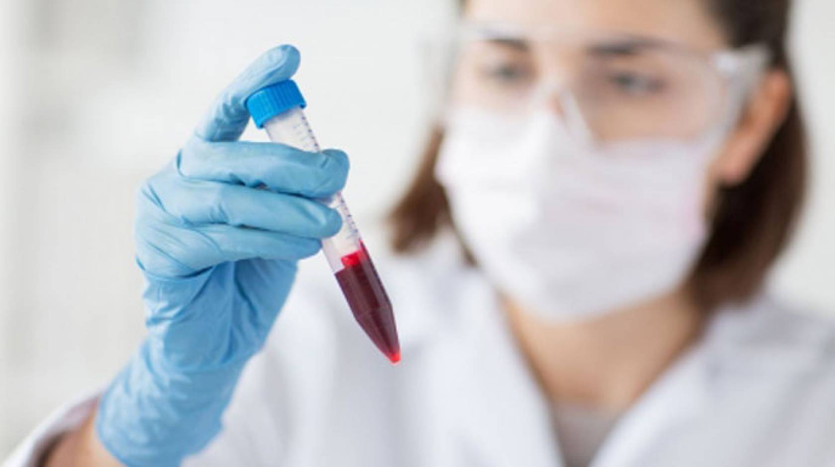 Female scientist holds blood vial
