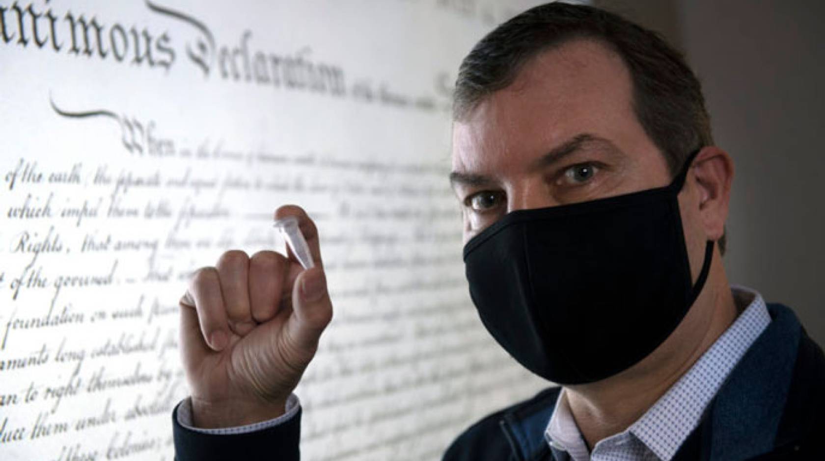 Chaput holds up a small object in front of the Declaration of Independence