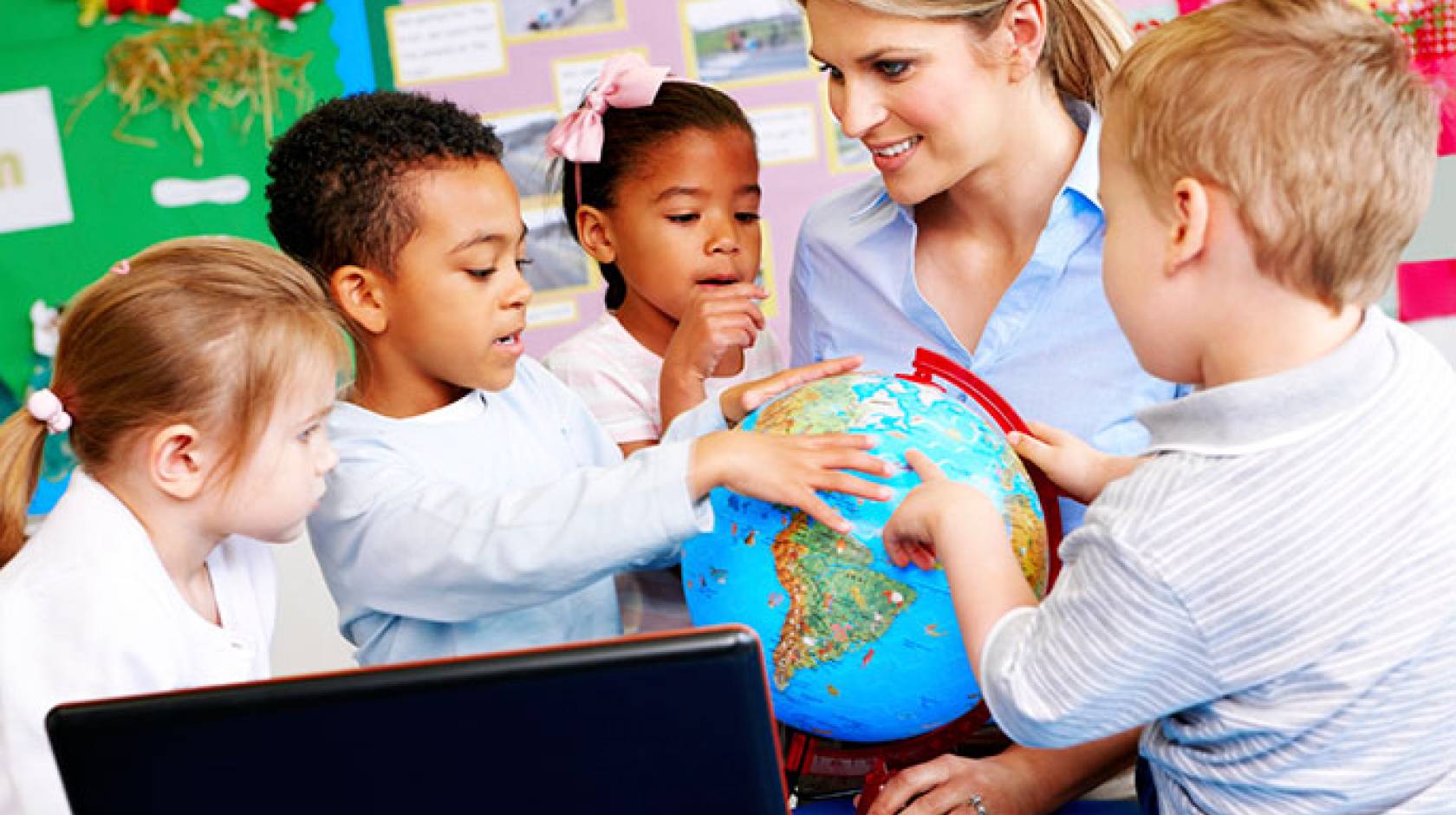 young children and teacher look at globe