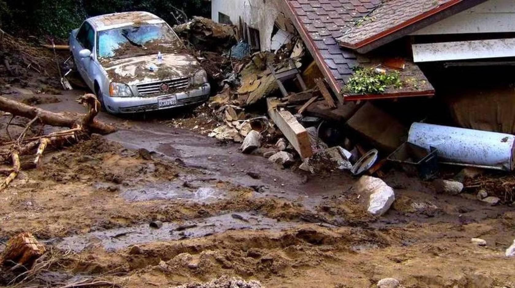 A car covered with mud and a house collapsed from a mudslide