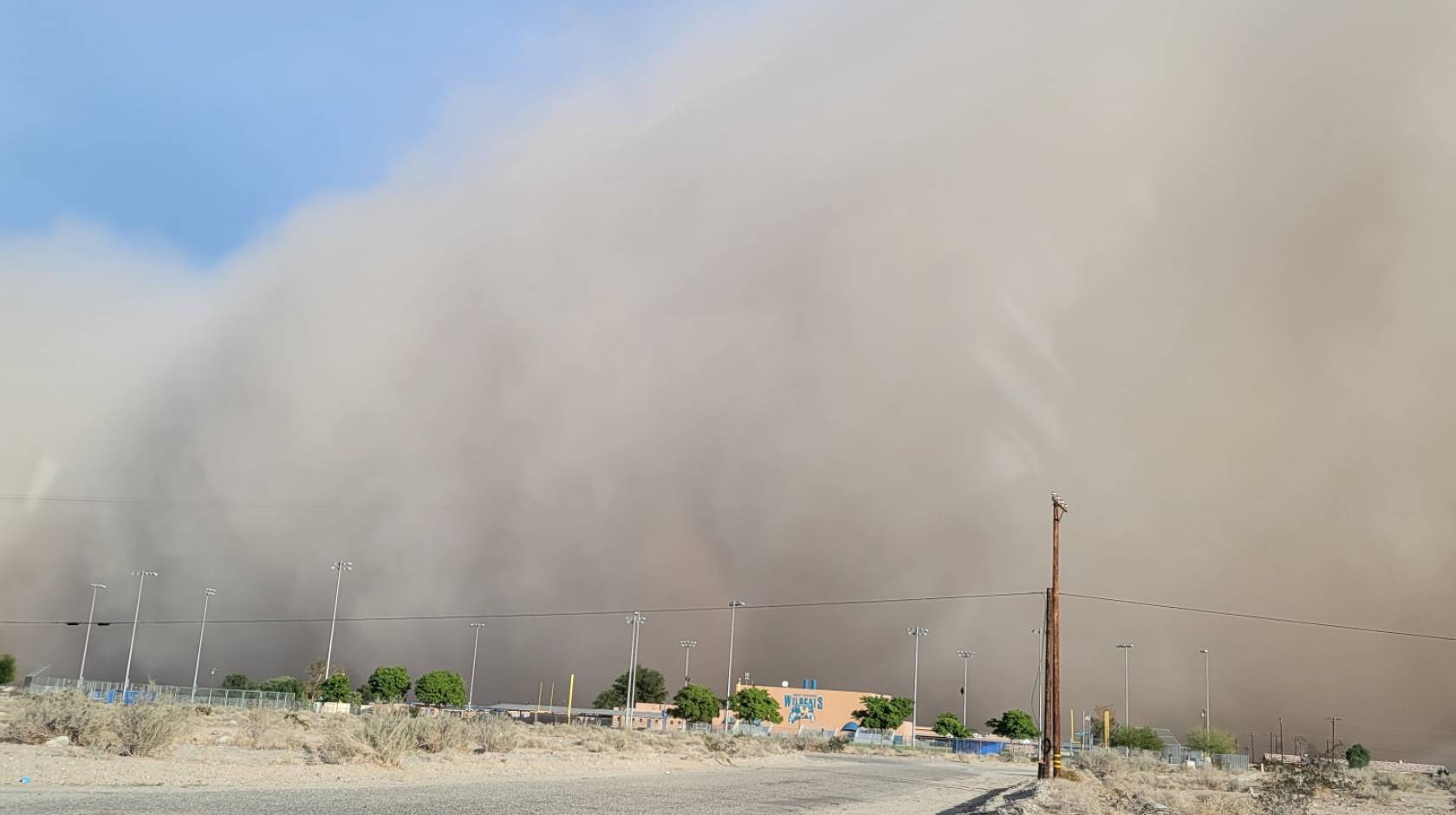 A dust cloud, taking up most of the picture, over a dirt road