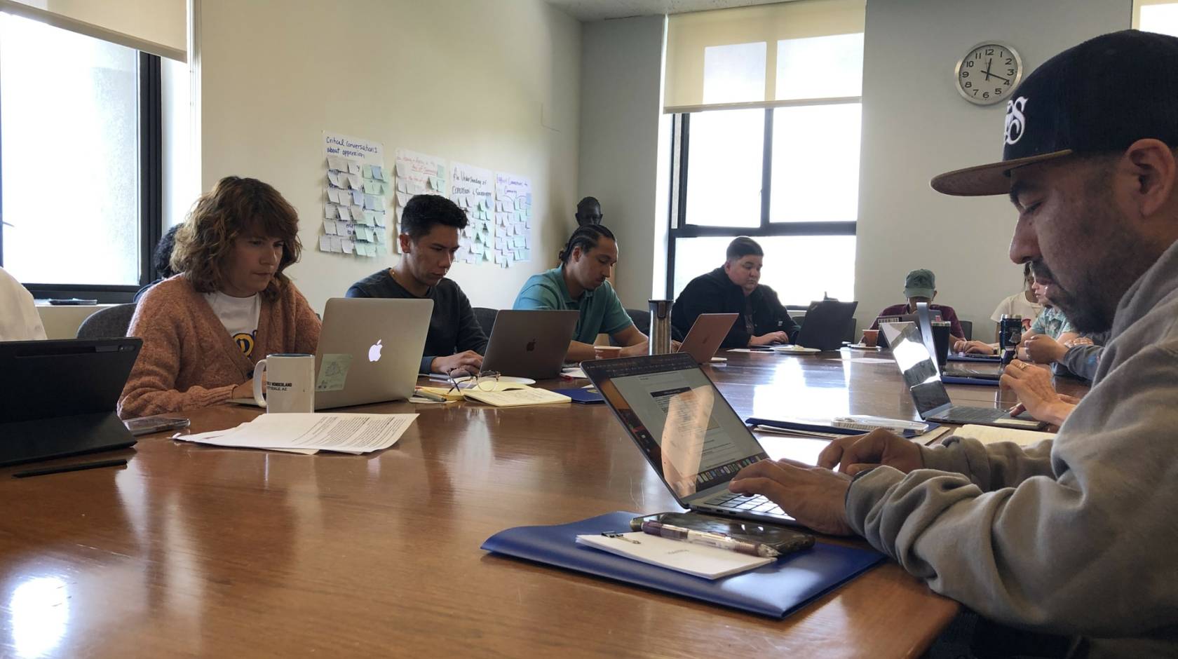 A diverse group of teachers working on laptops together on a wooden table