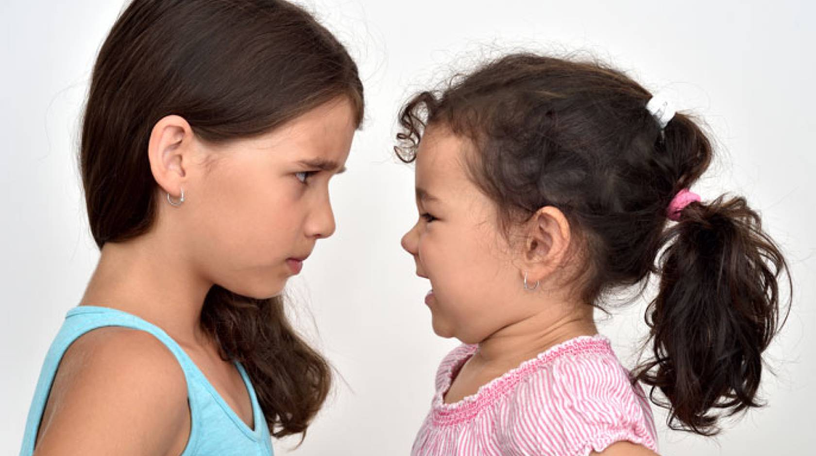 Two little girls look at each other eye to eye, one angry
