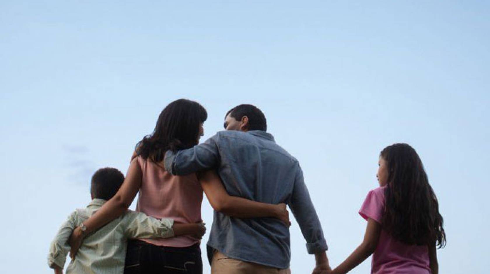 Family walking forward with sky background