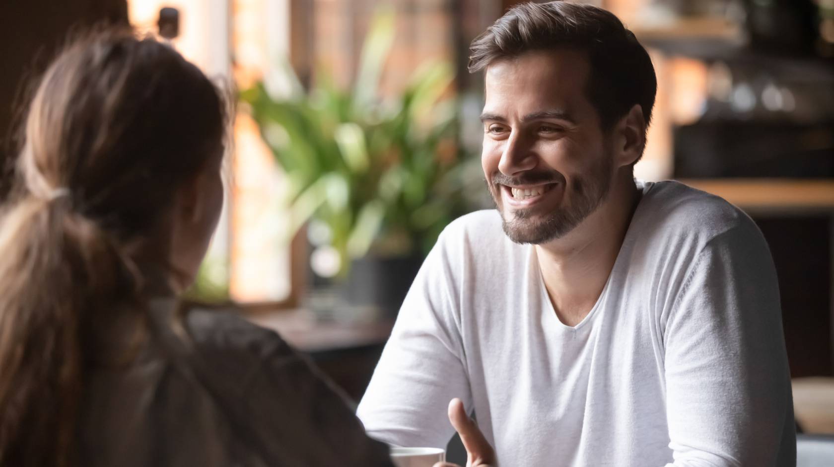 Woman looking at man smiling seated at the same table at a cafe