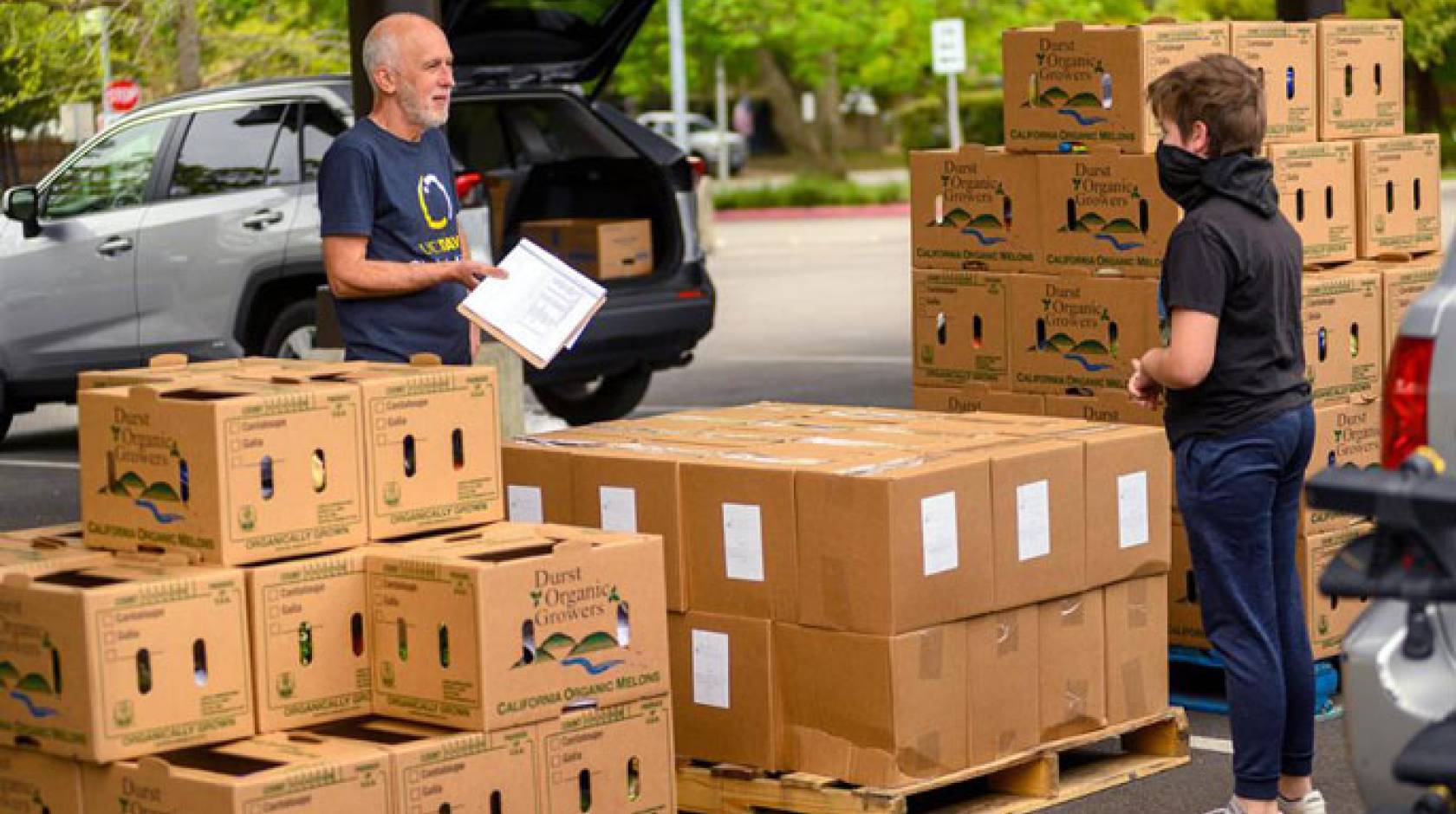 Robb Davis and teen boy organizing food boxes outside