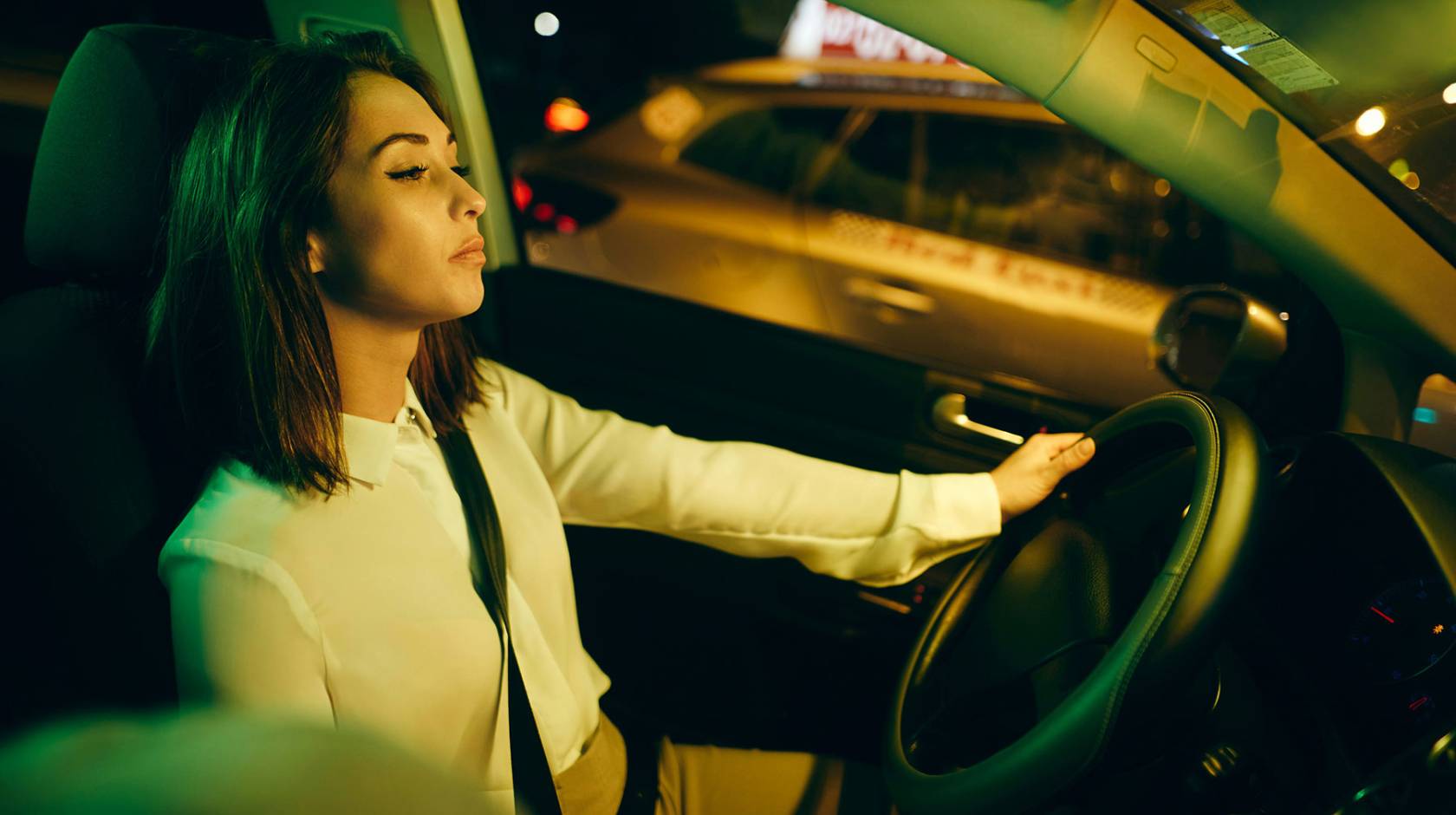 A person is leaning back and closing their eyes while driving a car.