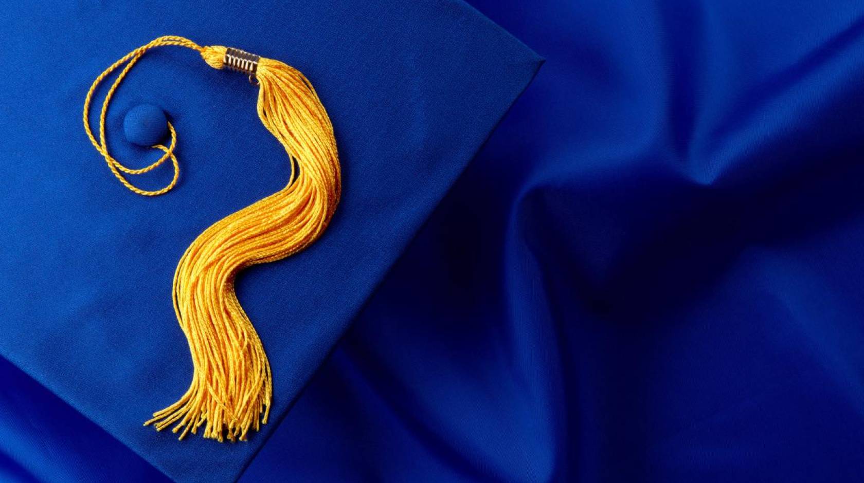 A blue graduation cap with gold tassle