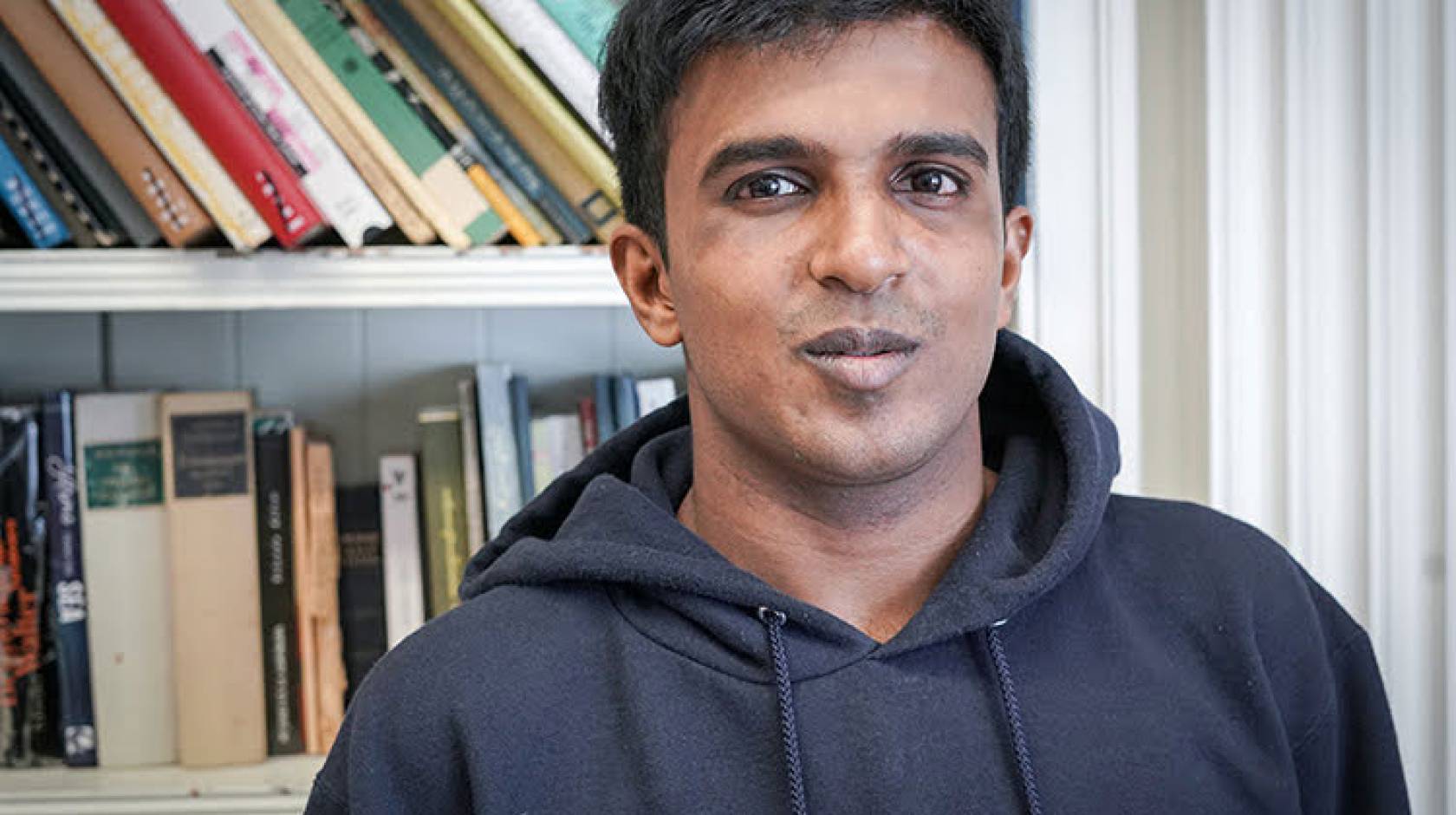 Hari Srinivasan in front of a bookcase