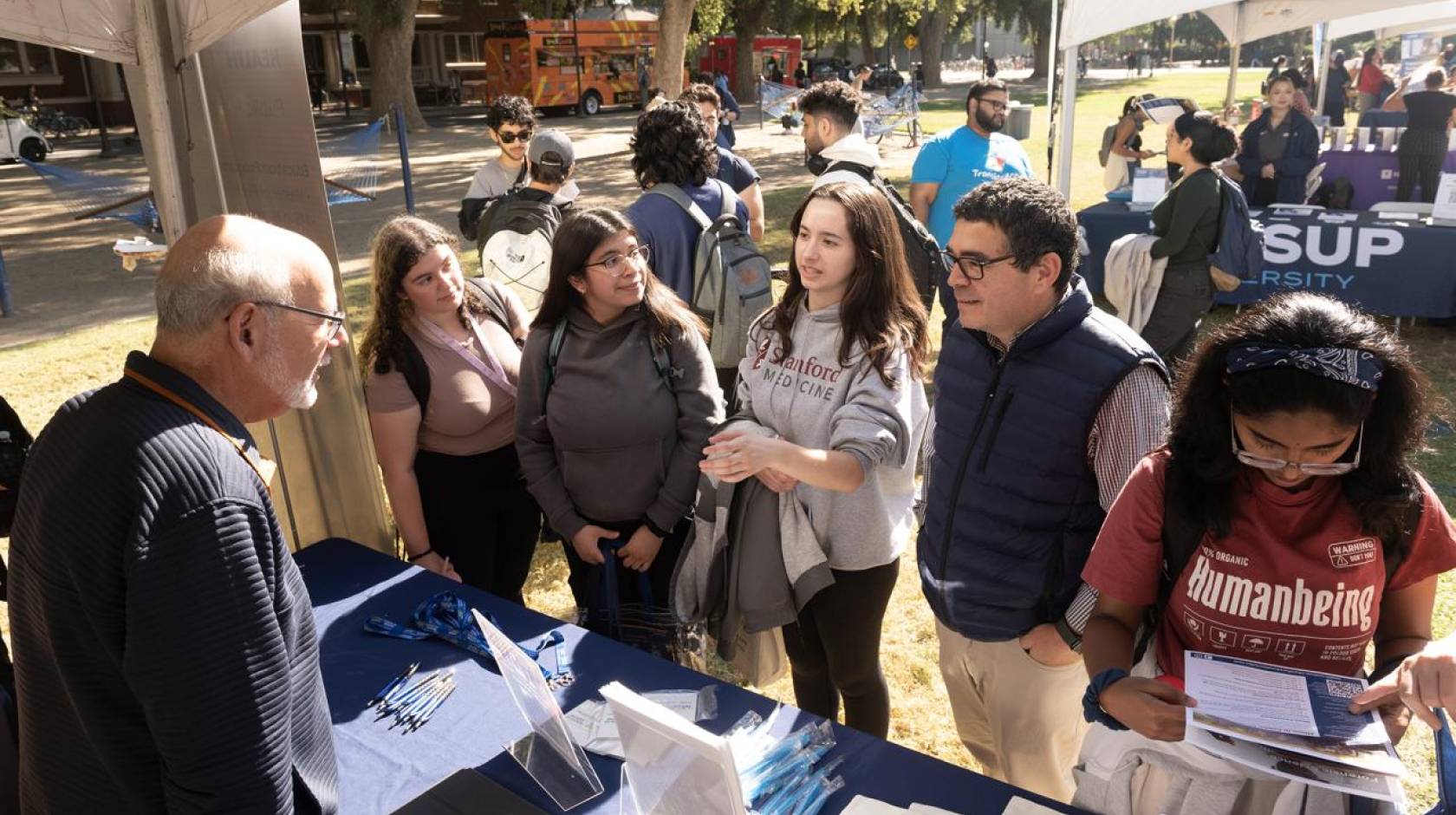 A number of undergraduates at a table outdoors during an event on campus