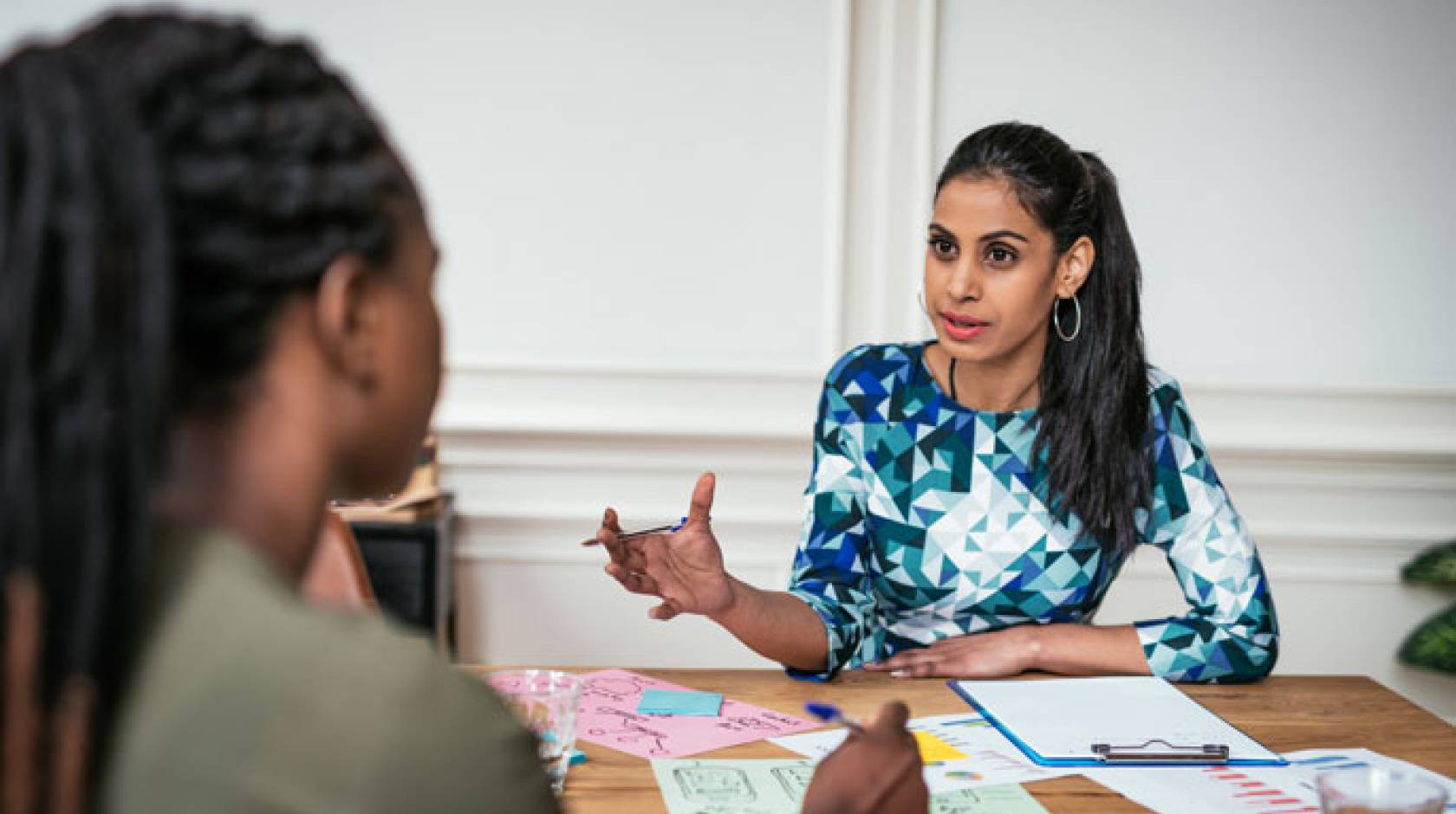 Two women of color discussing finances across a table