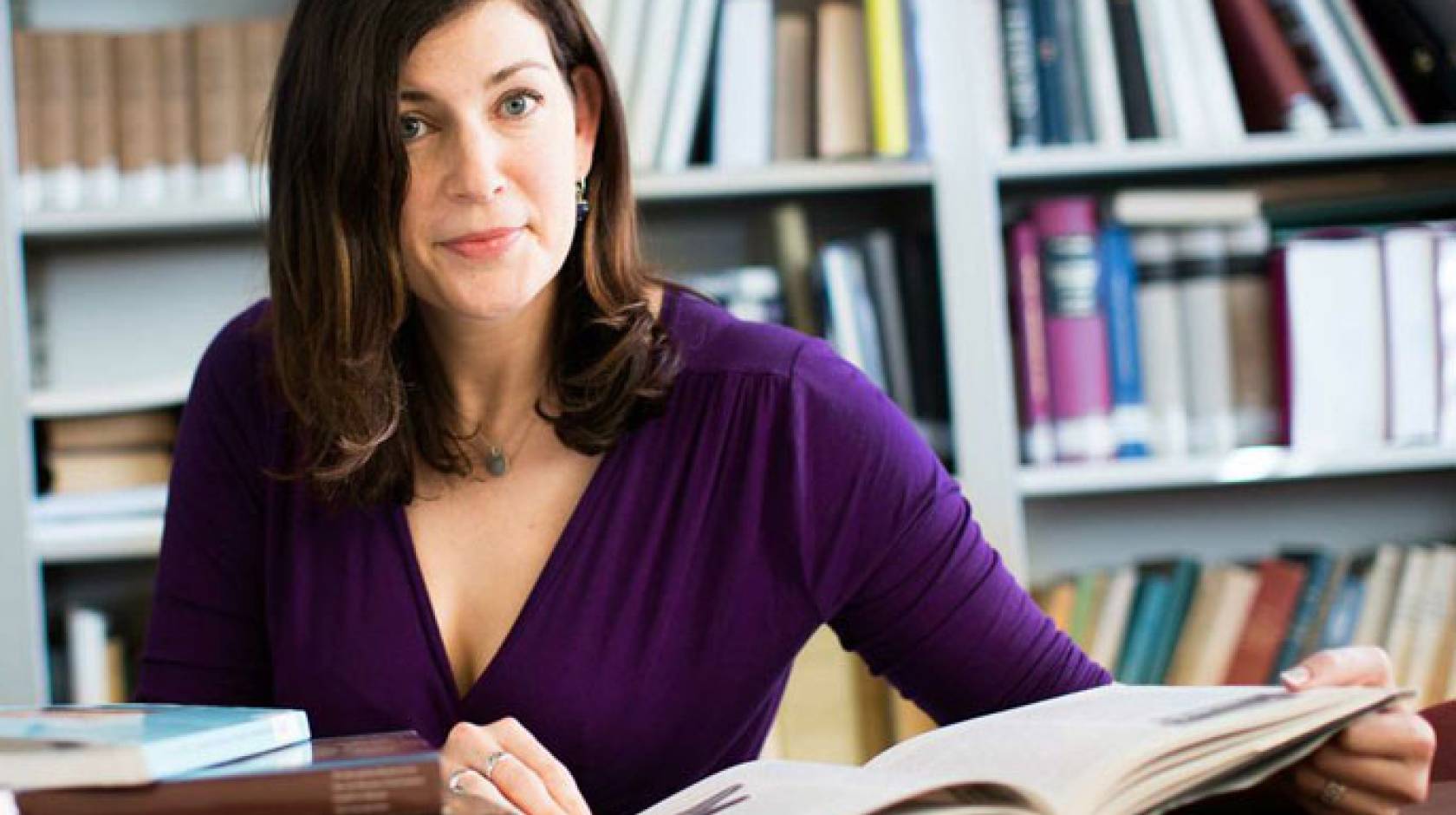 Kara Cooney at a desk with an open book