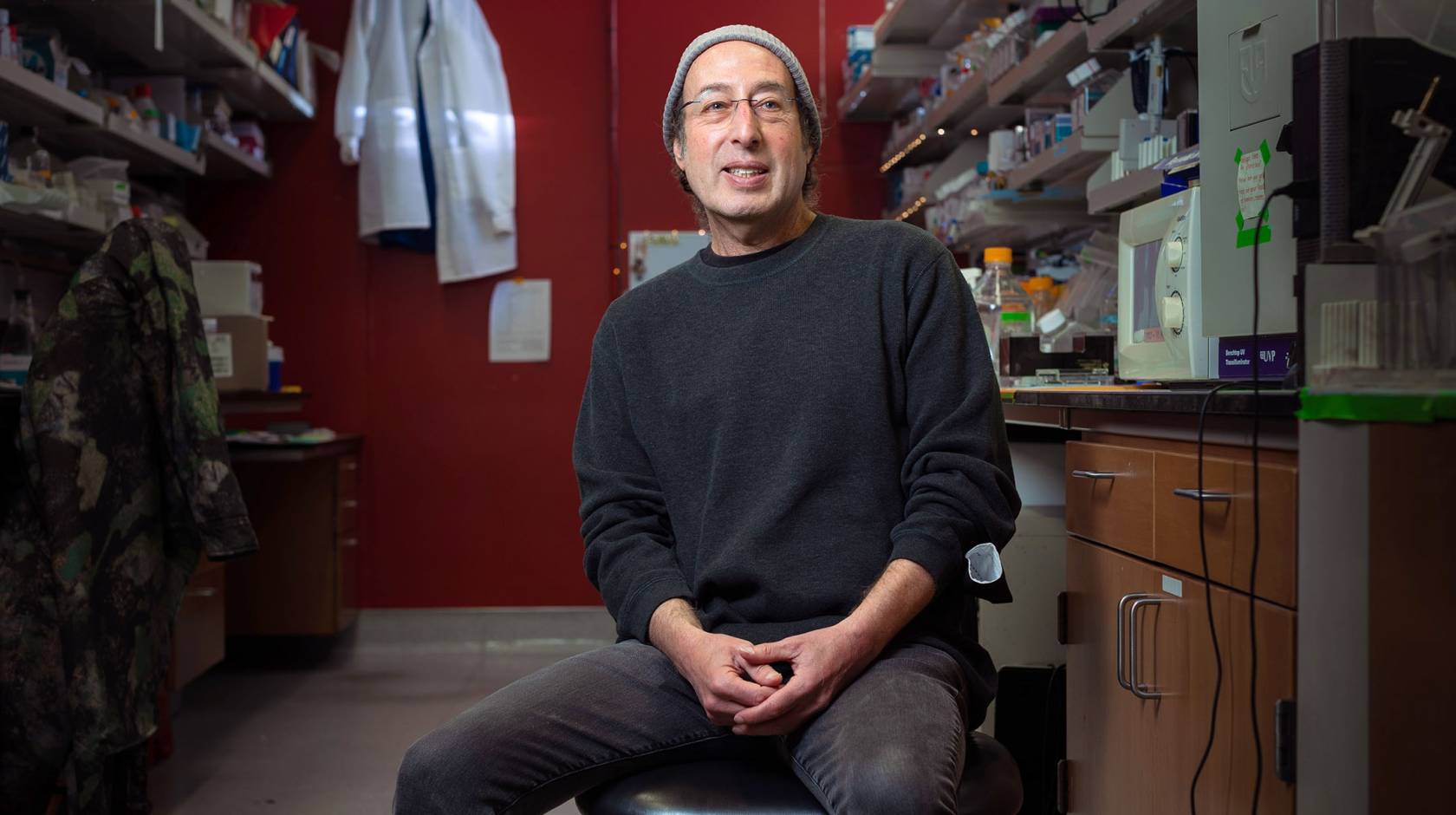 Kenneth S. Kosik seated in the lab, smiling in casual dress