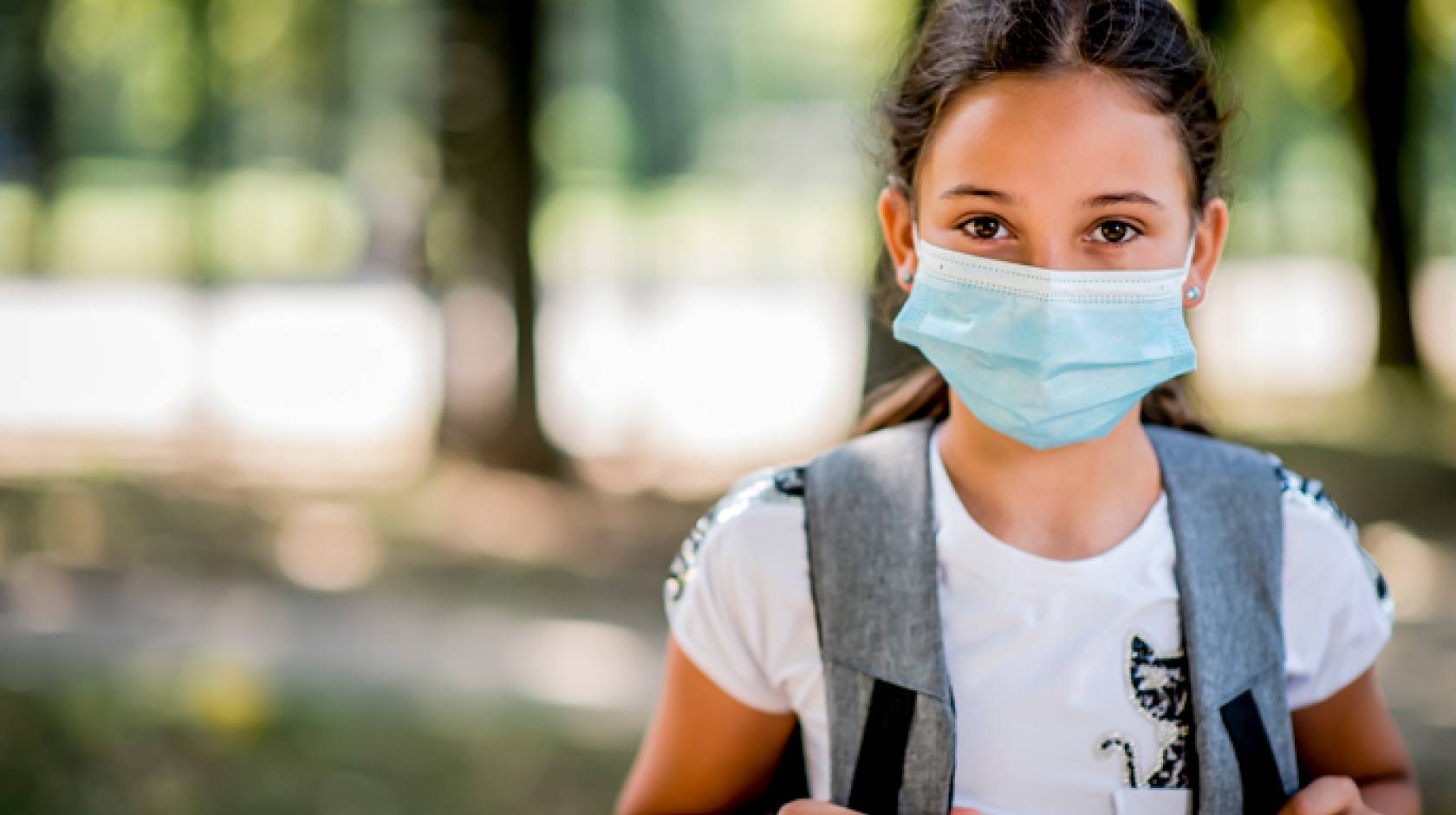 A child wearing a backpack and a mask