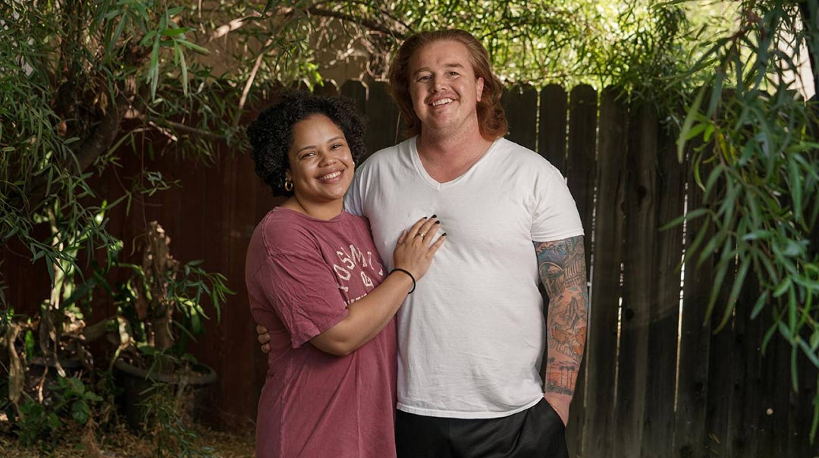 A woman with her hand on the chest of her male partner, who has long red hair