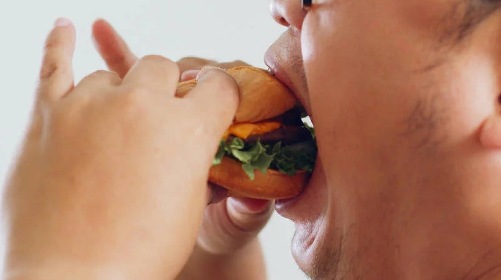 View of a man's mouth eating a burger dramatically