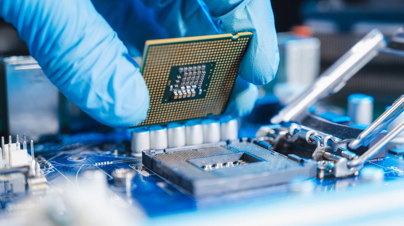 Close-up of a blue-gloved hand constructing a microchip