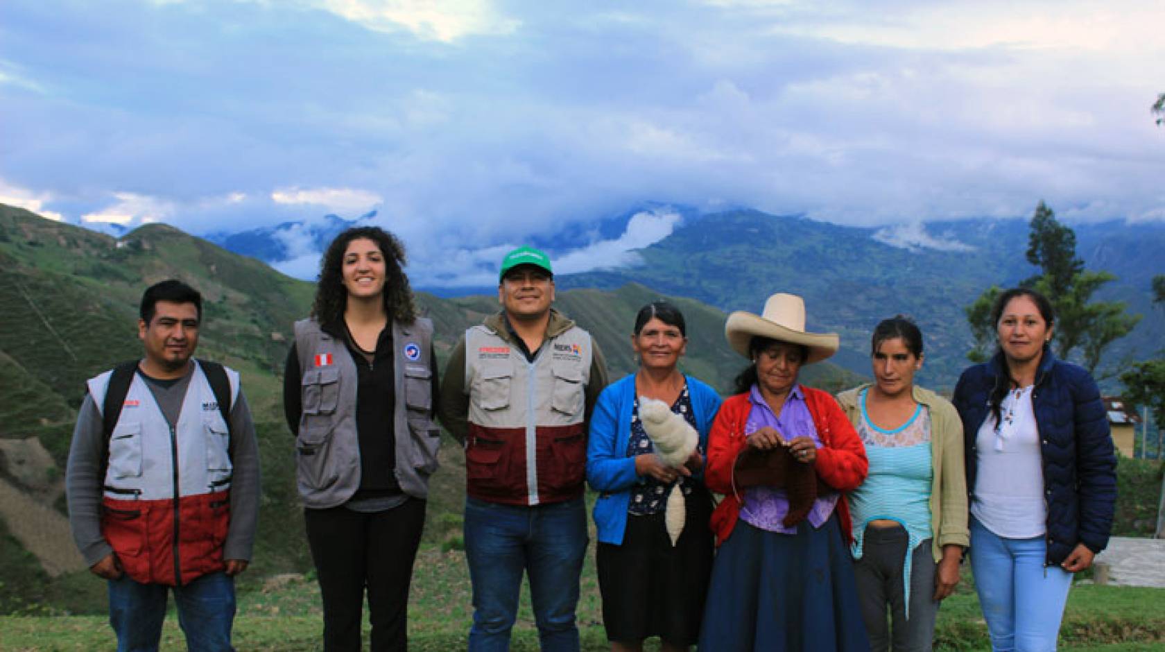 Neeka Mahdavi, a young Iranian-American woman, stands with her hosts in Peru with foggy, cloudy mountains in the background