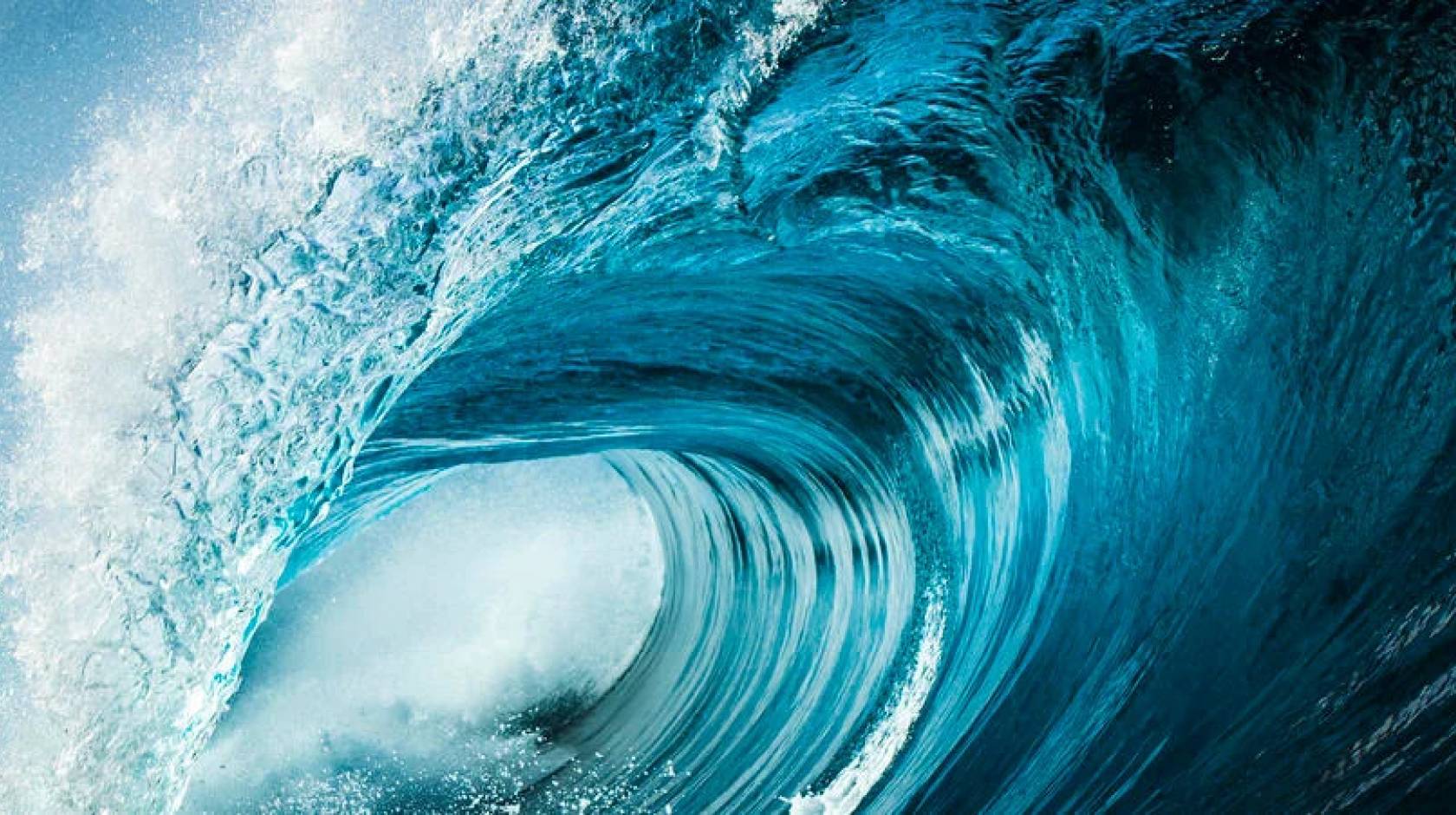 A very blue ocean wave about to crash, seen from the side