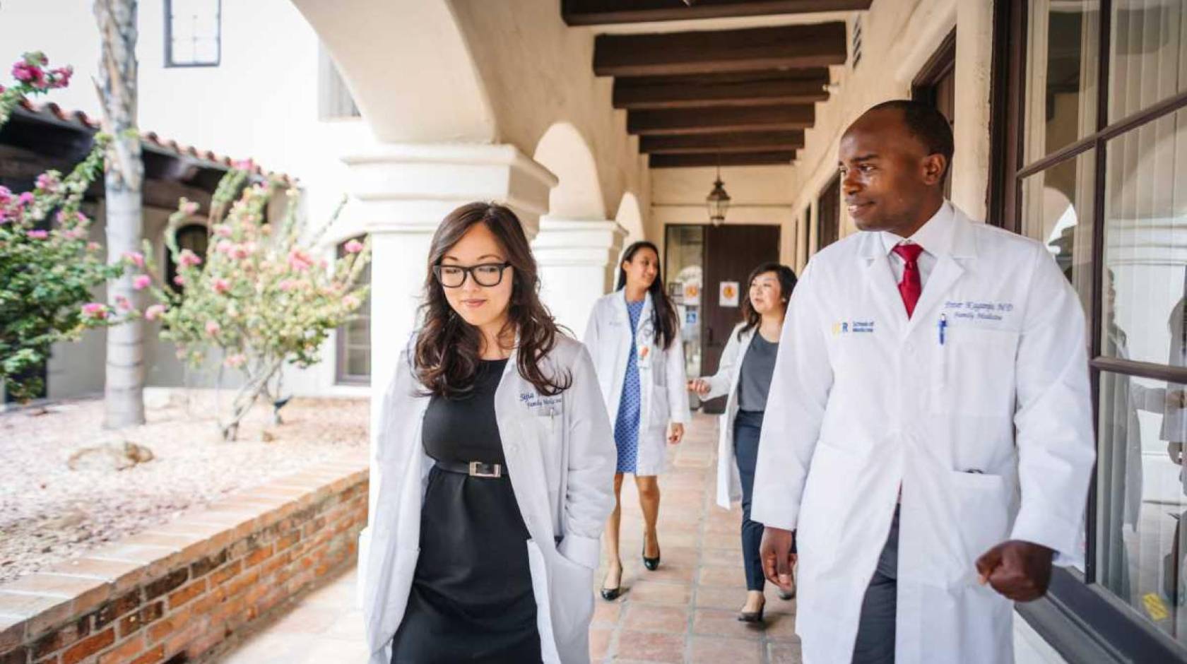 Doctors walking along a breezeway wearing white coats