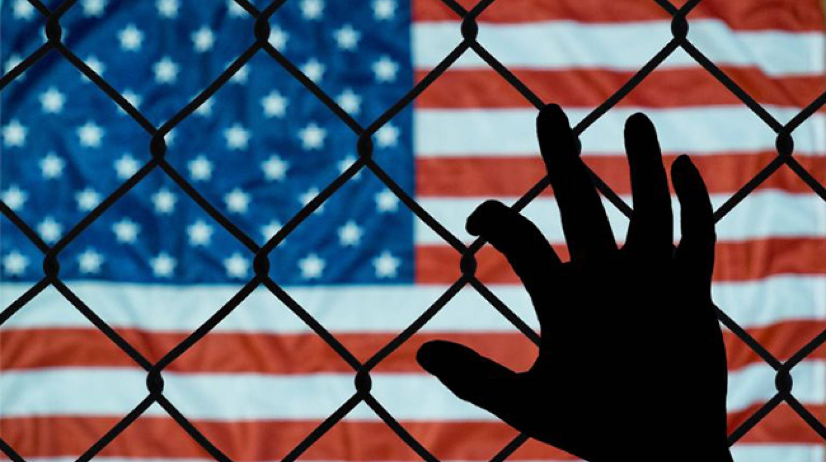 Hand on fence in front of an American flag