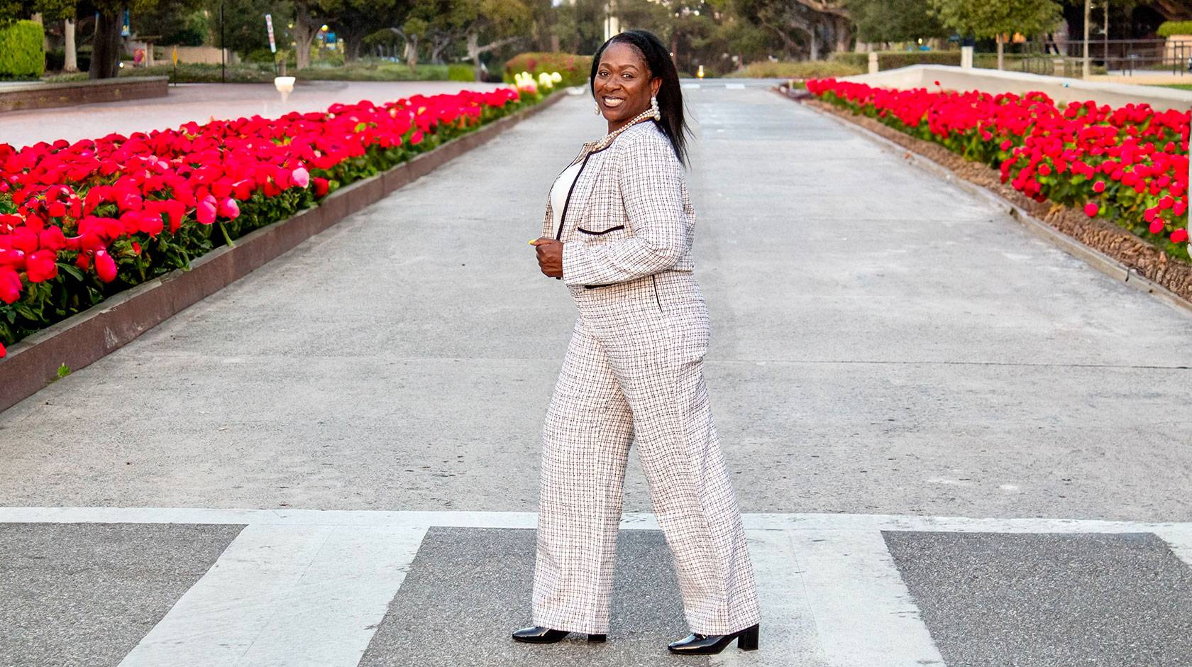 Sonya Brooks walks in a crosswalk across a street lined with red tulips