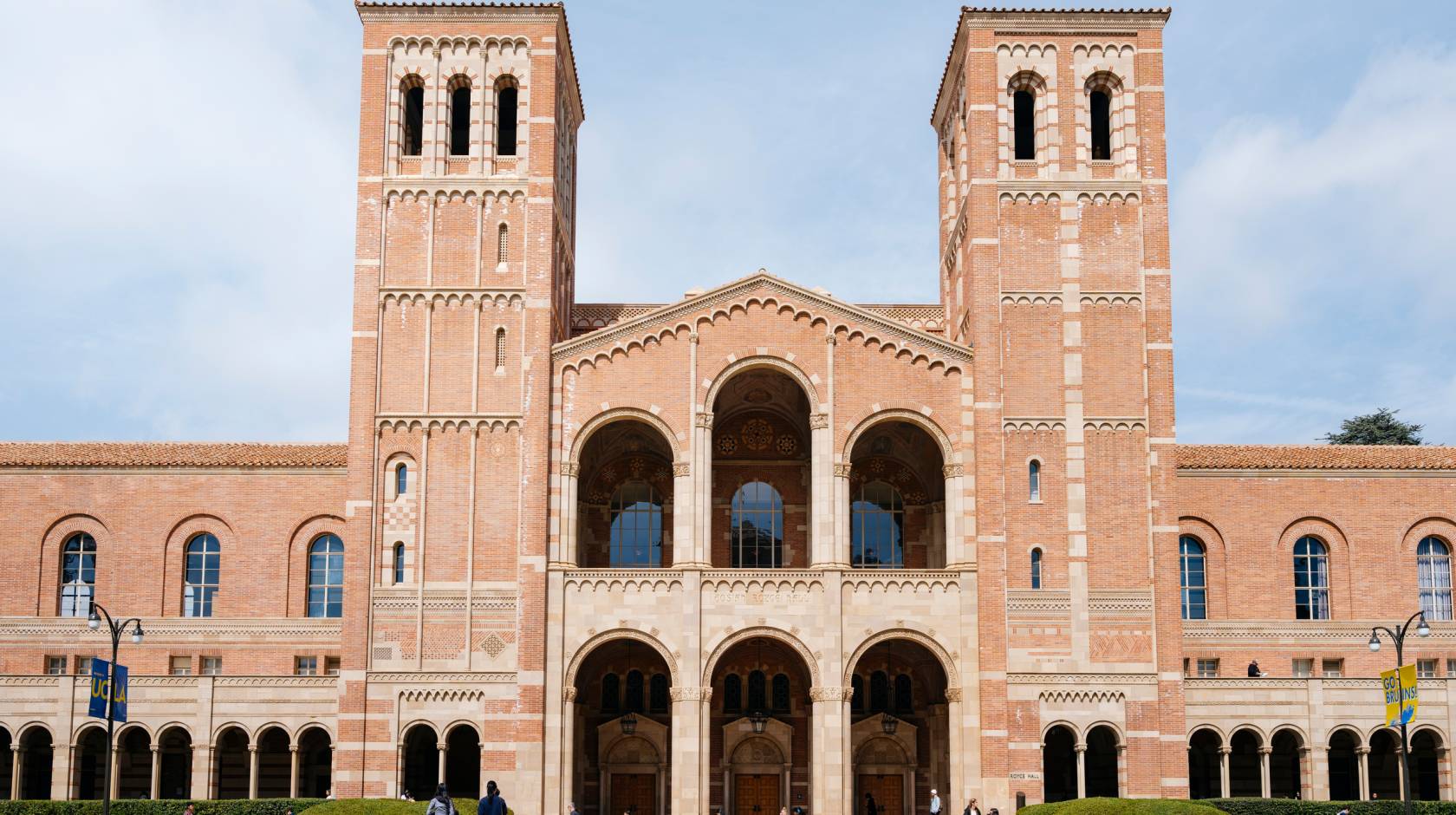 UCLA Royce Hall, a light brick building with two towers, against a slightly cloudy bright blue sky