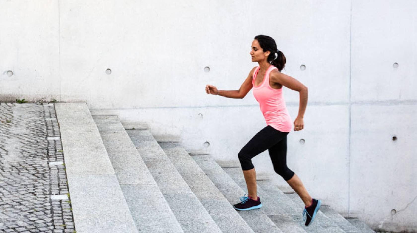 Woman jogging up grey steps outdoors