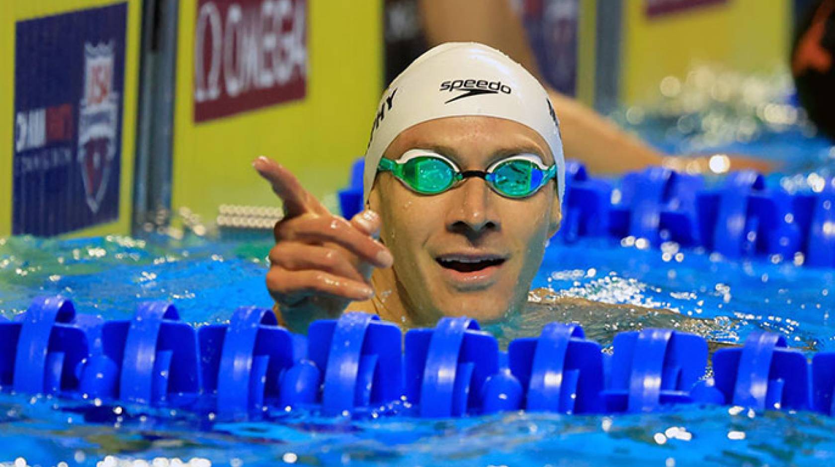 Ryan Murphy pointing from the pool in cap and googles just after a race