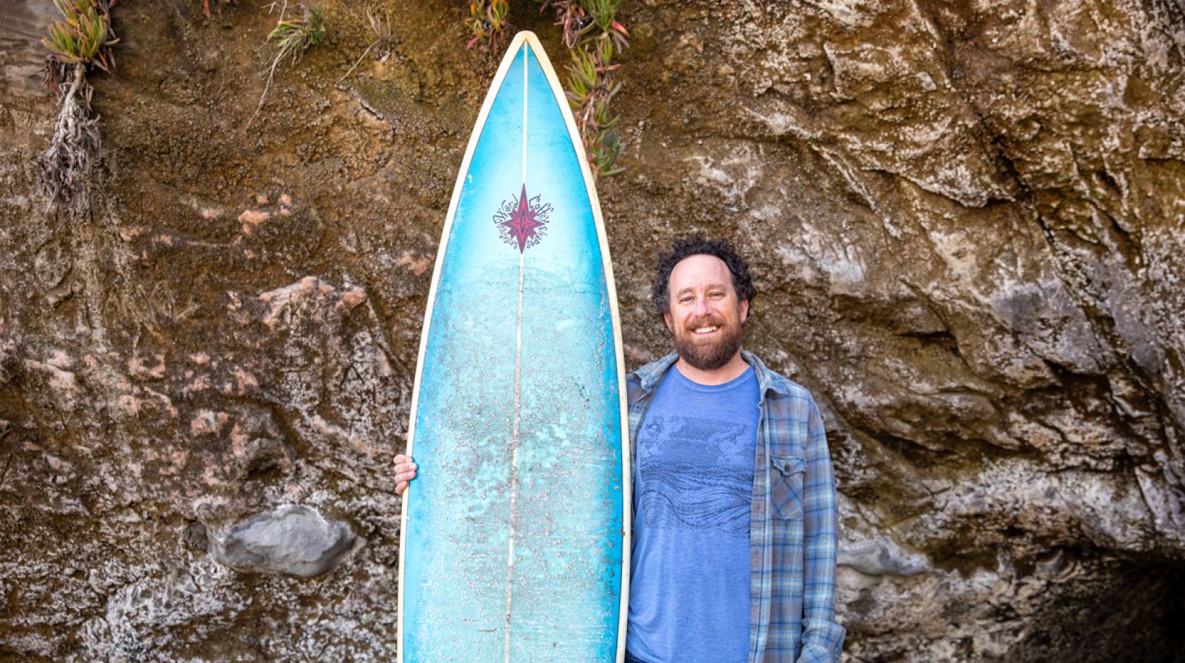 David Schulkin stands with his surfboard