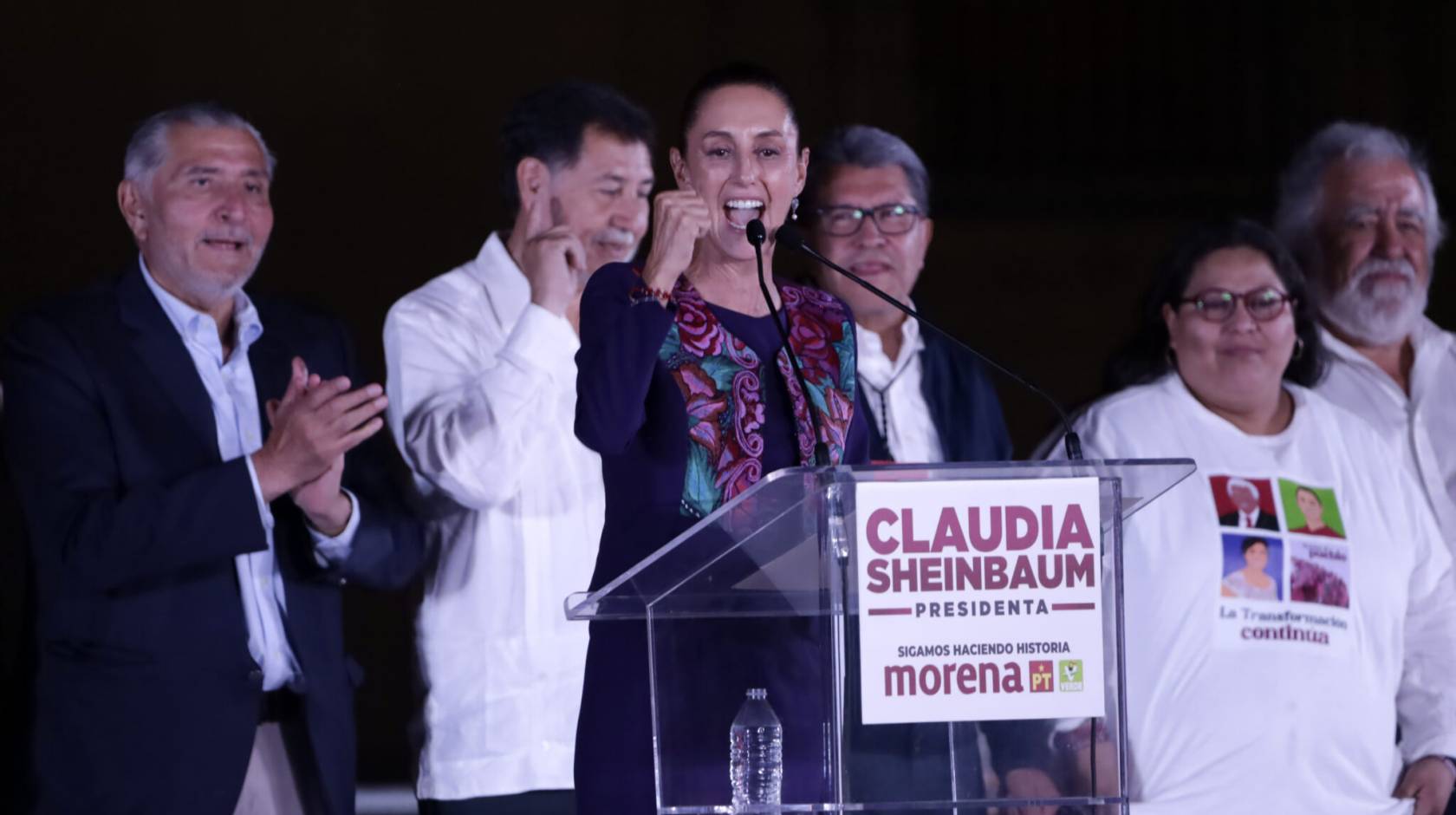 Claudia Sheinbaum pumps her first at a podium at a political rally