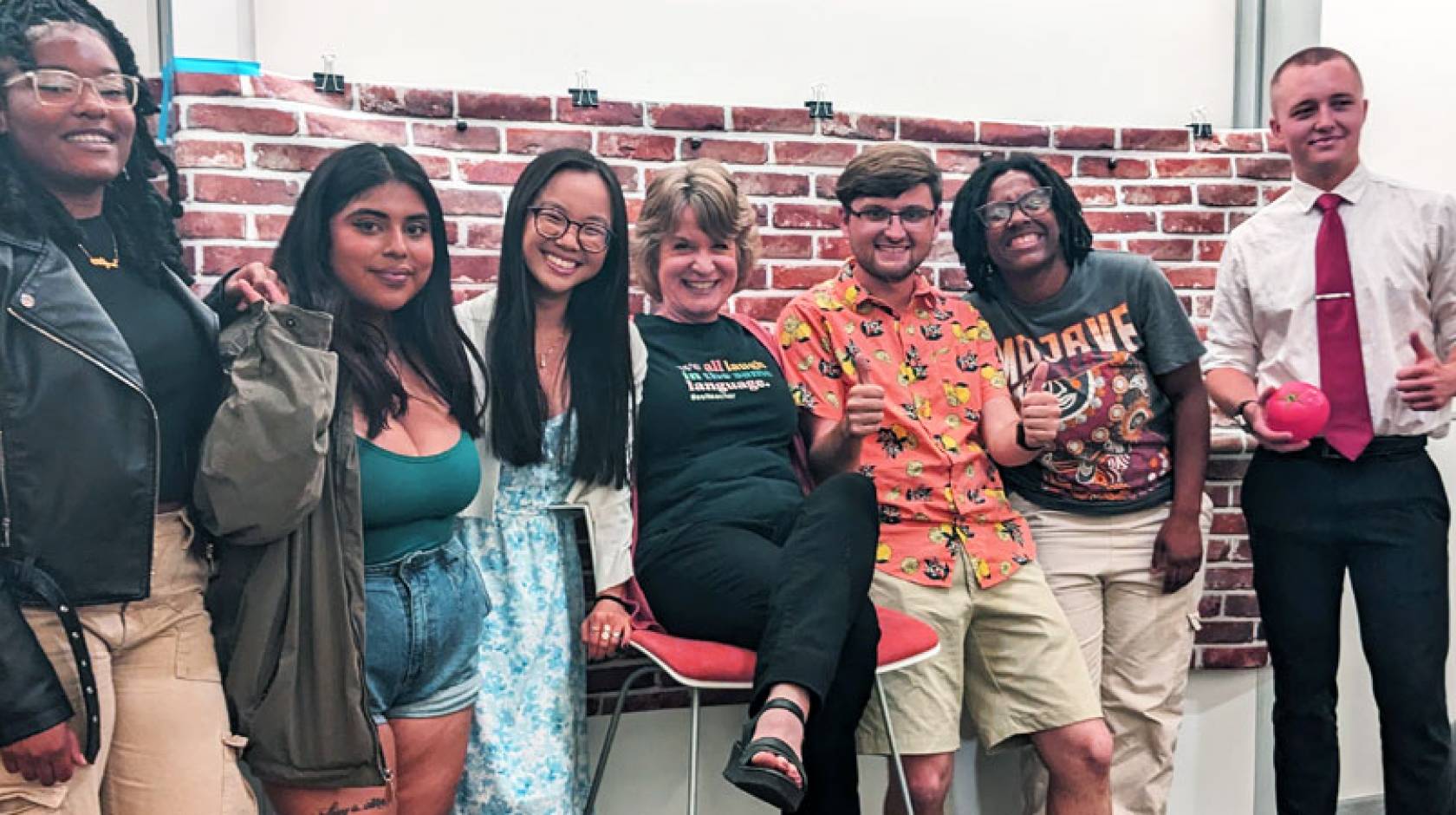 Six students and a professor on a standup comedy set, smiling for the camera with arms around each other