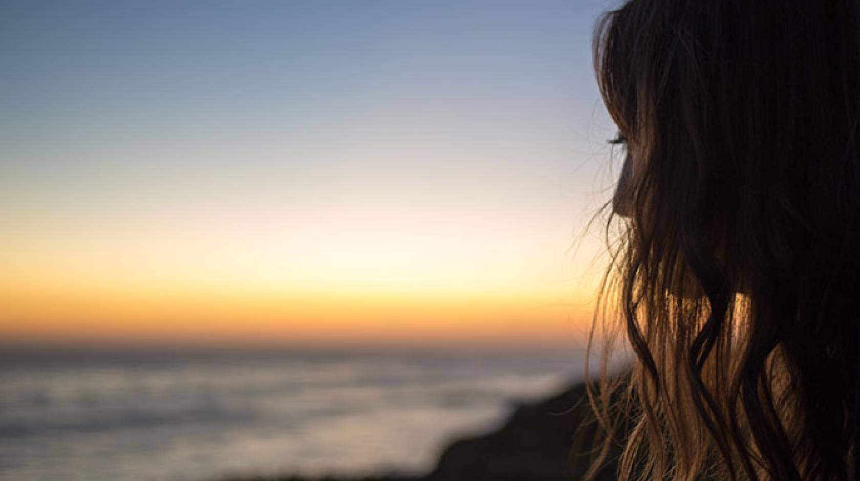 Teen staring at the beach away from the camera