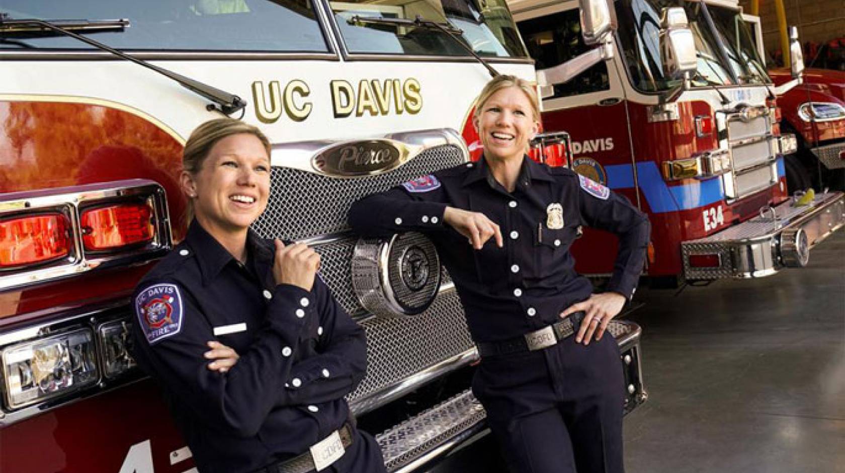 Twin firefighters pose in front of a fire truck